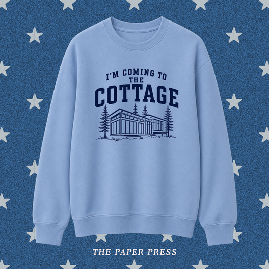 Heated Rivalry coded sweatshirt featuring “I’m Coming to the Cottage” collegiate-style text with a detailed cottage and pine tree illustration, hand-printed by The Paper Press.