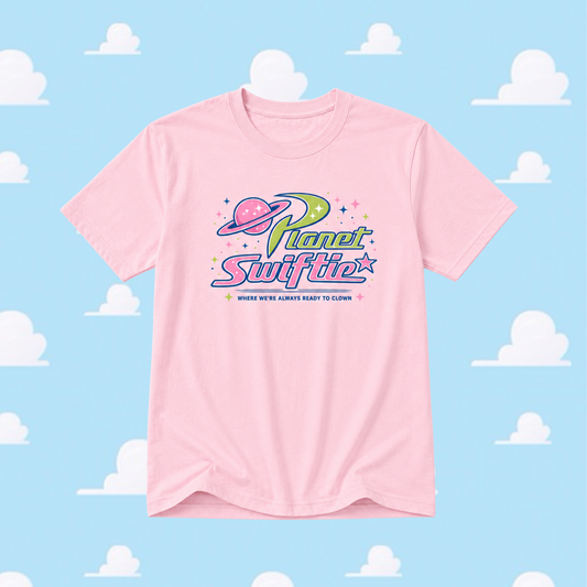 Pink t-shirt with 'Planet Swiftie' logo on a blue background with cloud patterns