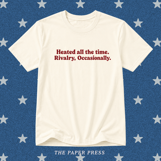 Vanilla Heated Rivalry coded T-shirt featuring the slogan “Heated all the time. Rivalry, Occasionally.” in dark red retro lettering, hand-printed by The Paper Press.