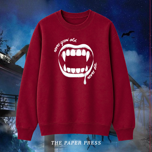 Lost Boys coded red sweater featuring a white vampire fang graphic and “Never Grow Old, Never Die” slogan, hand printed by The Paper Press.