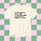 An off-white short-sleeve t-shirt with black printed text on the chest, displayed against a pink and green checkered background.