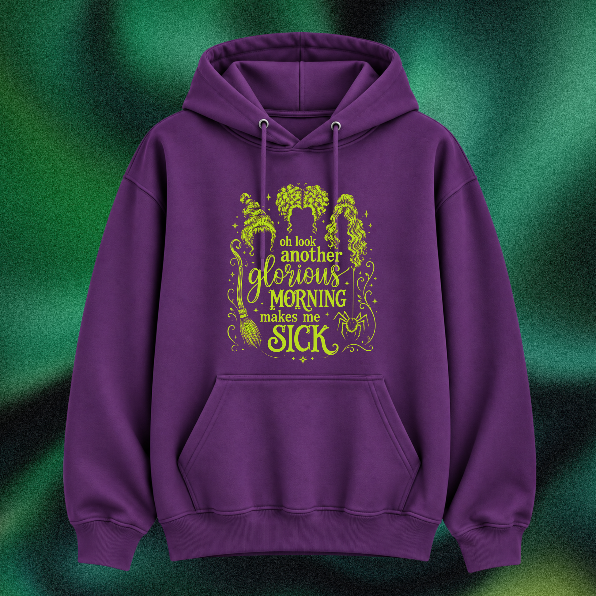 A purple pullover hoodie with a green graphic print on the front, featuring the text 'oh look another glorious MORNING makes me SICK' with witch illustrations, shown against a dark green textured background.