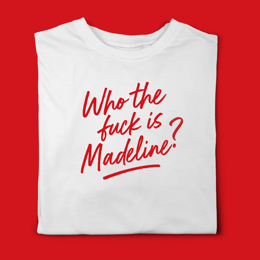 Folded pastel pink T-shirt with a bold red handwritten slogan reading ‘Who the fuck is Madeline?”